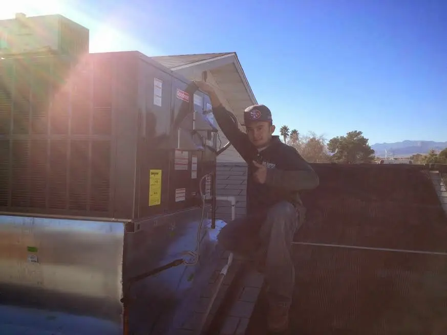 HVAC technician performing Heat Pump Repair on a rooftop unit in Scott